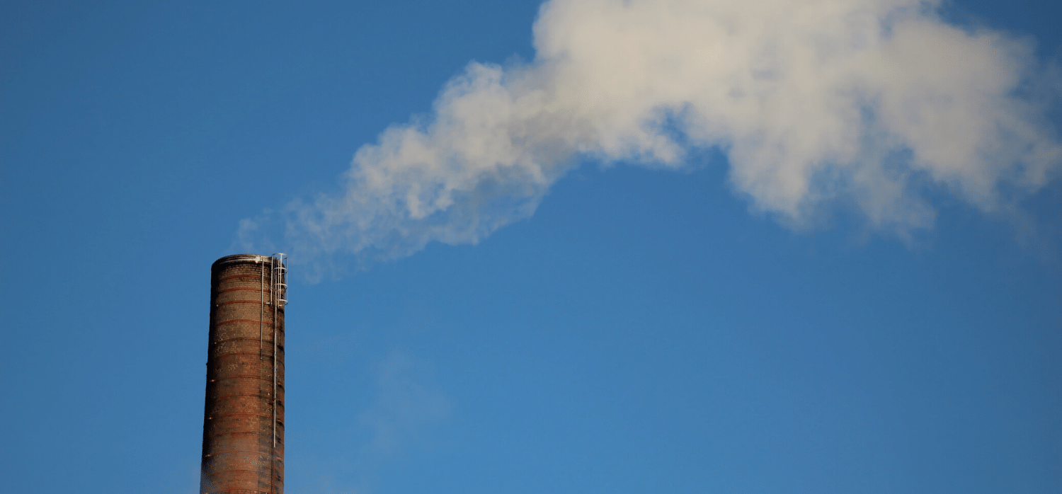 A thin long factory chimney emitting smoke