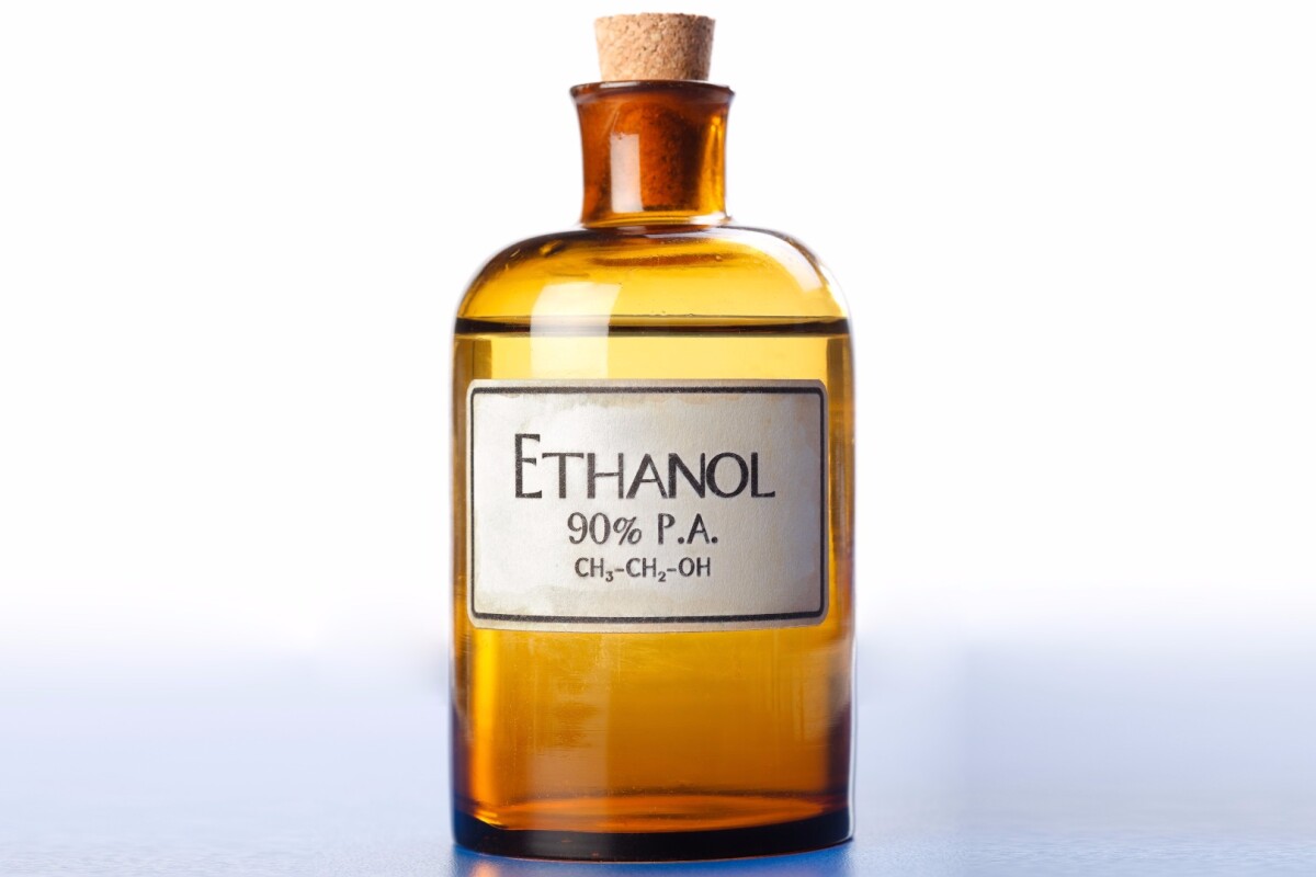 A covered transparent brown jar having a white label with the word ethanol written on it