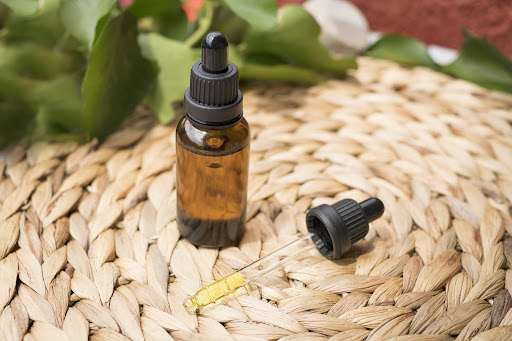 A closed CBD oil tincture bottle and a tincture dropper on a mat