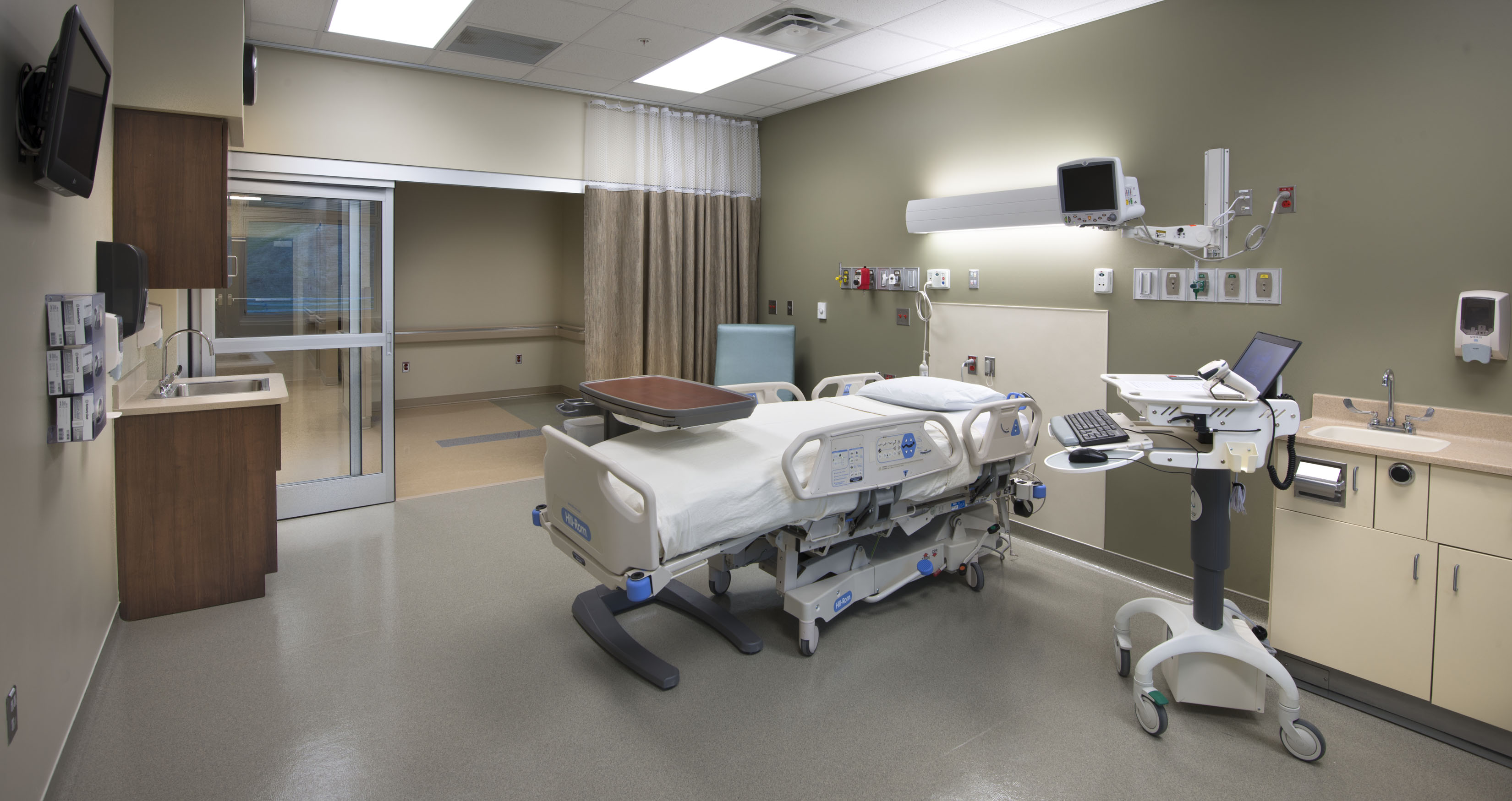 An intensive care unit with a bed, a desk, and some functional machines