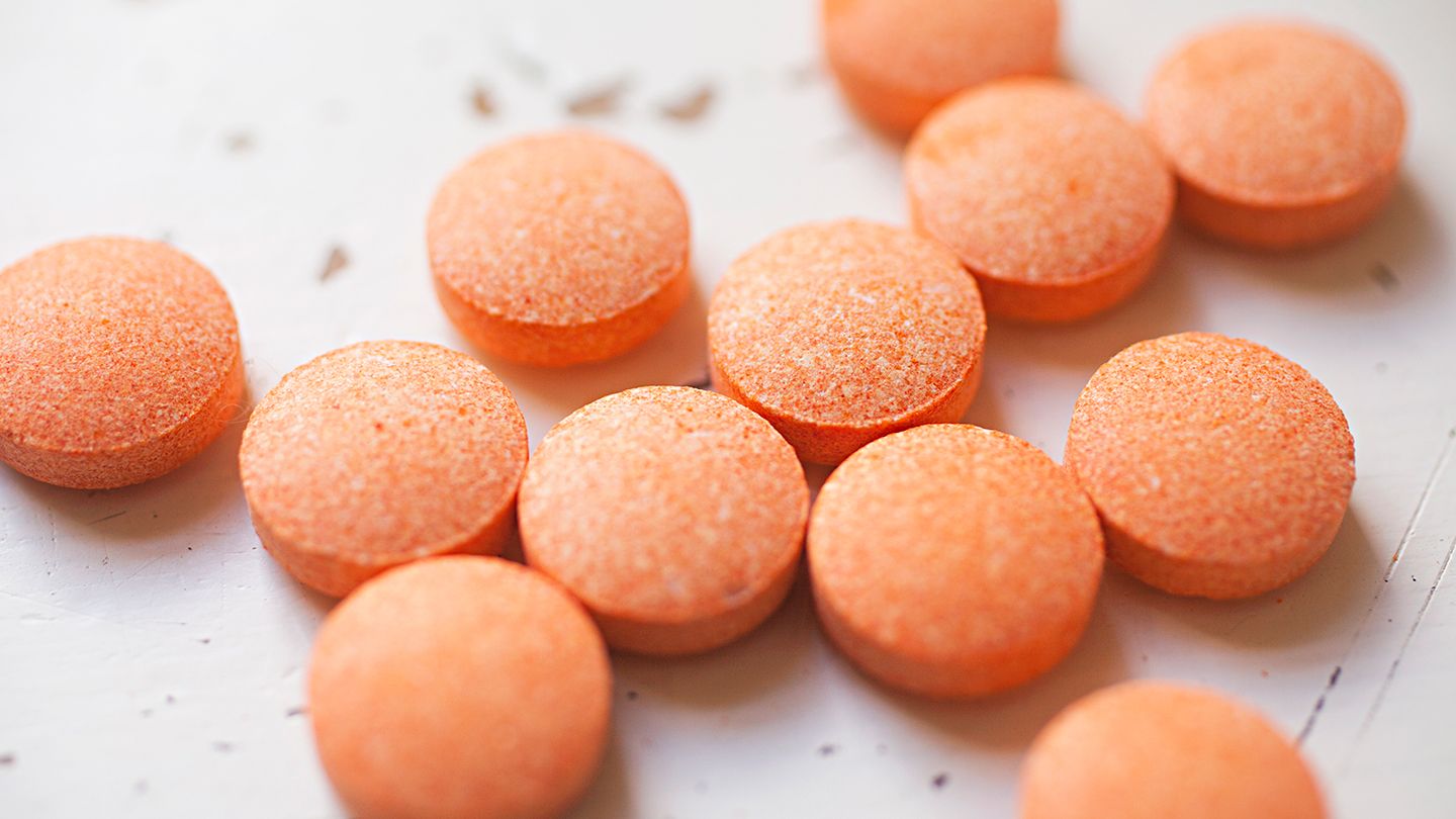Twelve pills of orange vitamin C laying close to each other