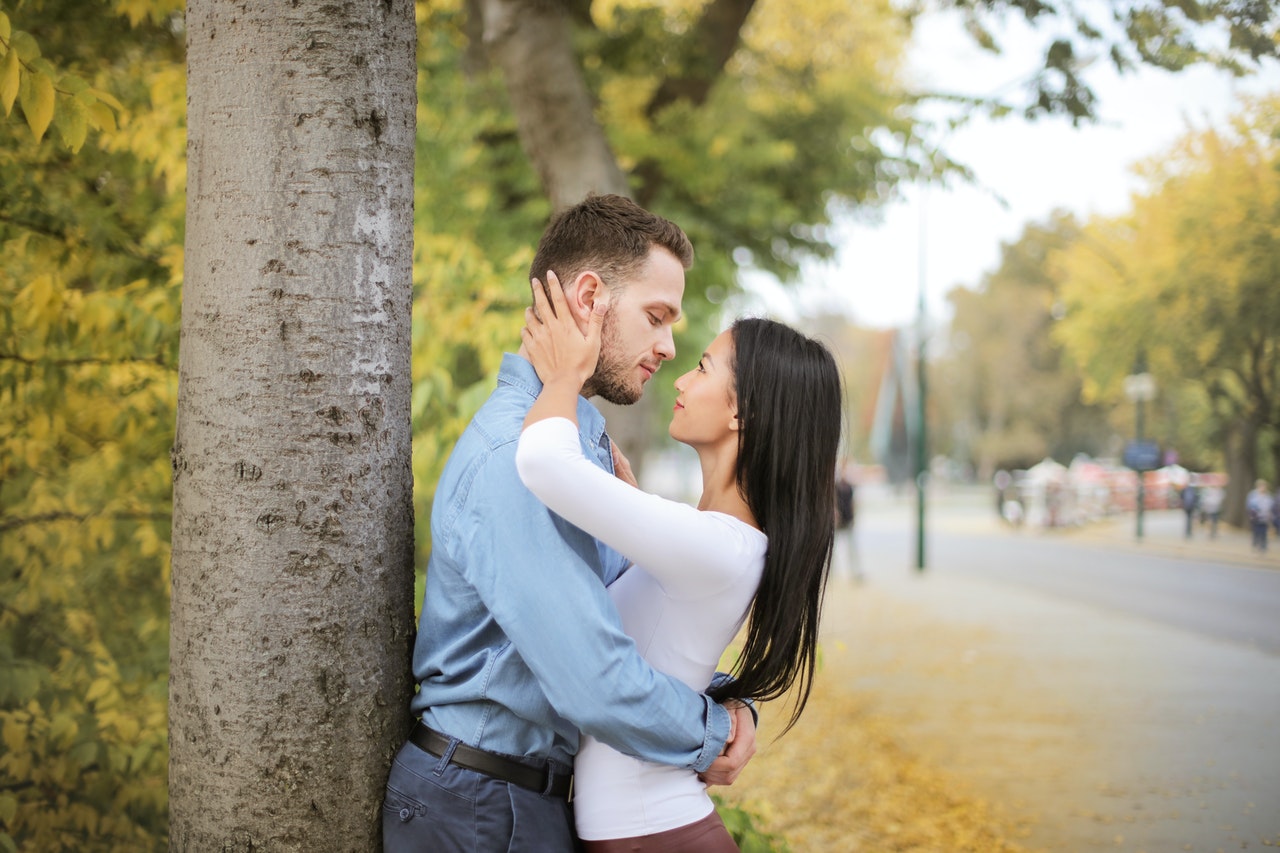 Couple Hugging And Looking at Each Other While Standing Next to a Tree