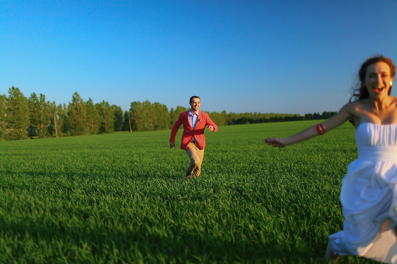 A Man Chasing His Woman on the Grass Field