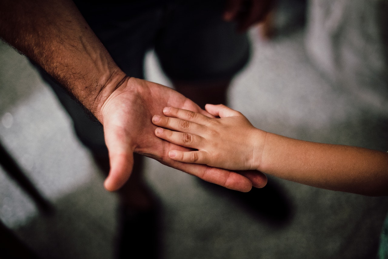 A Child's Hand On Top Of His Father's Hand