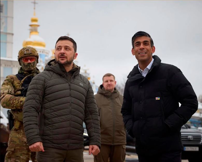 UK Prime Minister Rishi Sunak standing with Ukraine President Volodymyr Zelensky with two security guards behind them